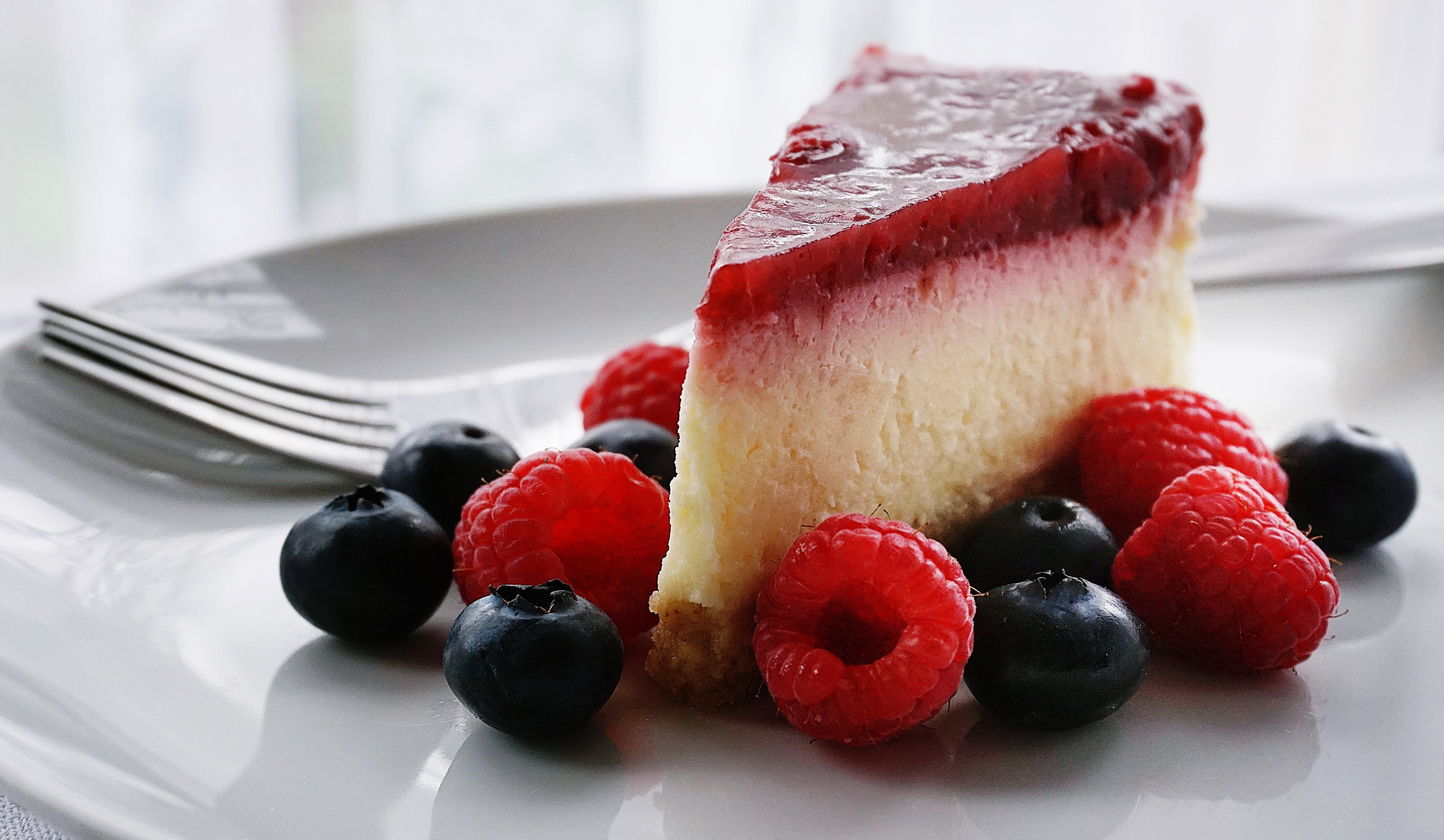 cheesecake slice with strawberries and blueberries in plate